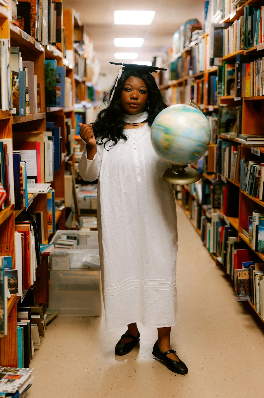 Latin American woman in a beige trench coat holding a magnifying glass in a library